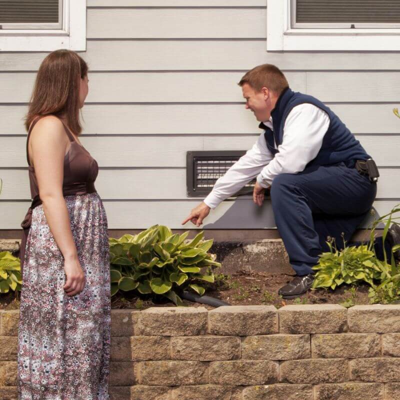 Franklin Pest Solutions tech showing woman foundation on house