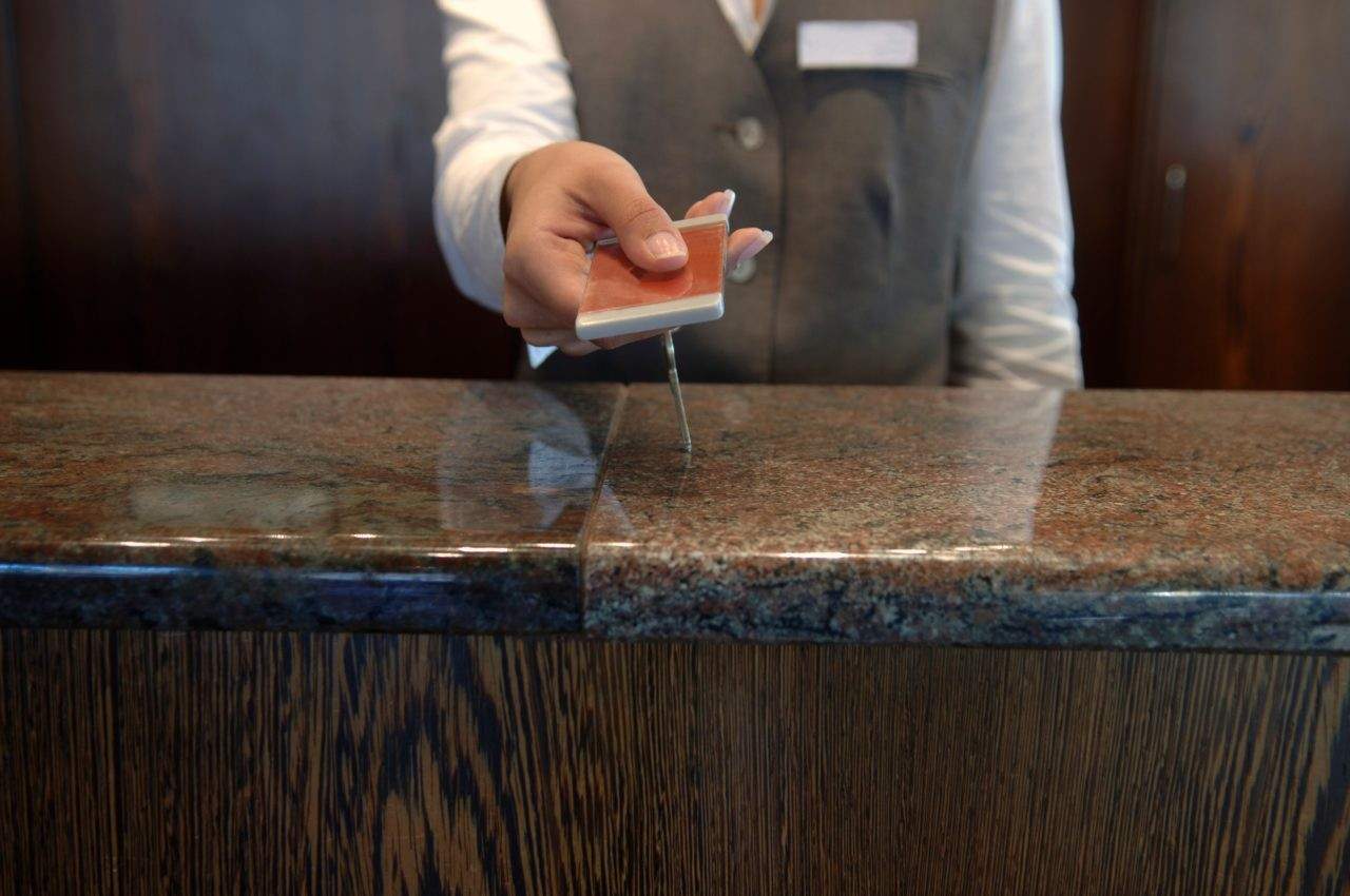 Hotel front desk staff handing a key card to guest at reception counter