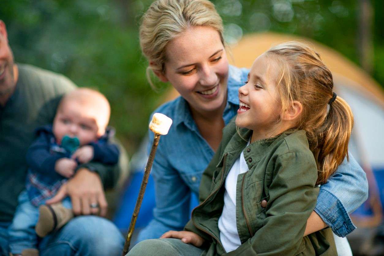 Family gathered around a campfire, roasting marshmallows at a campsite outdoors